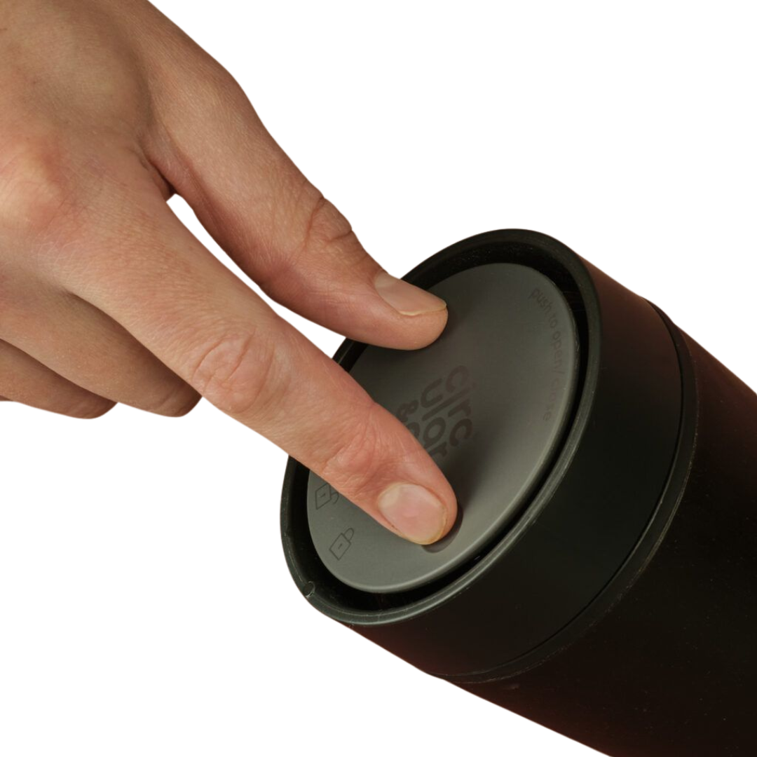hand pressing the lid of a reusable coffee cup from coffee waste.