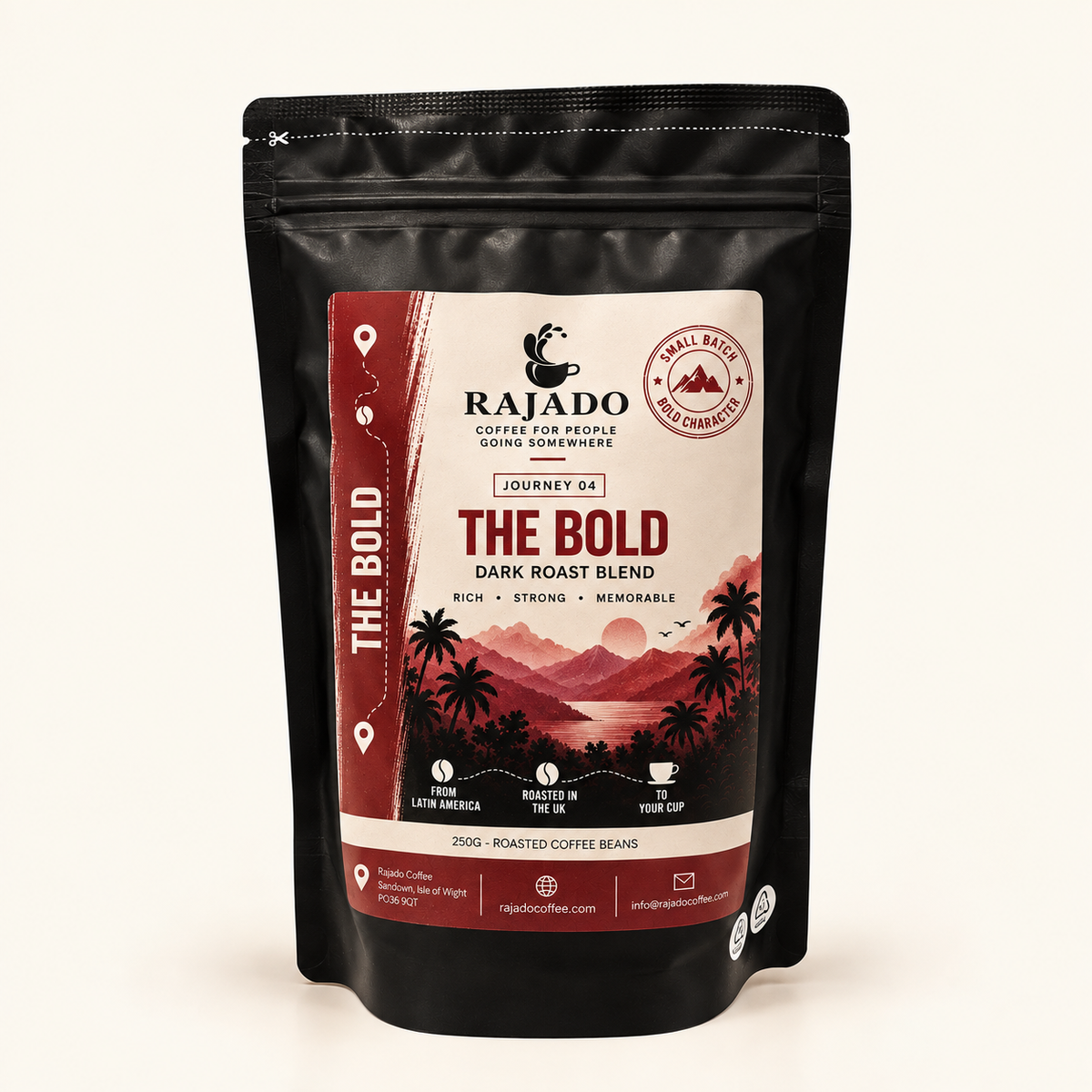 A black stand-up pouch of Rajado Coffee 'The Bold' dark roast blend, featuring a cream and red tropical landscape label, set against a plain off-white background.